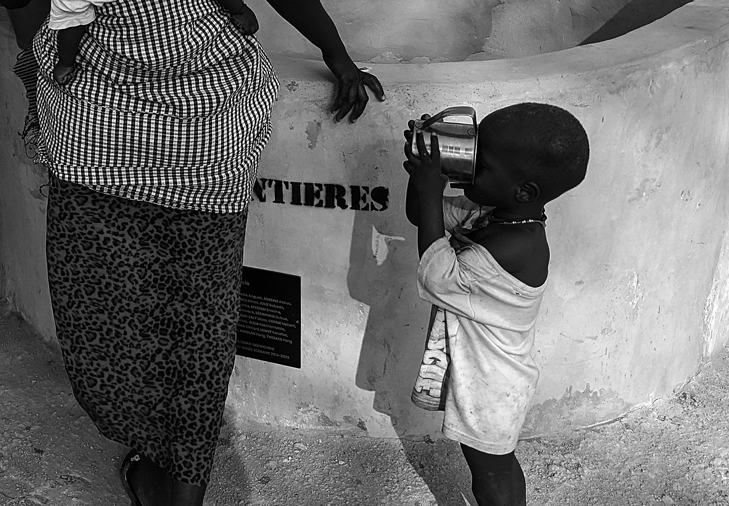 Un jeune enfant boit l'eau d'un puits dans un village isolé au Sénégal